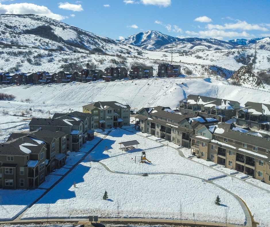 Aerial view of Wasatch Springs Near Park City Homes For Sale with snow-covered roofs and grounds, nestled against a backdrop of rolling hills.
